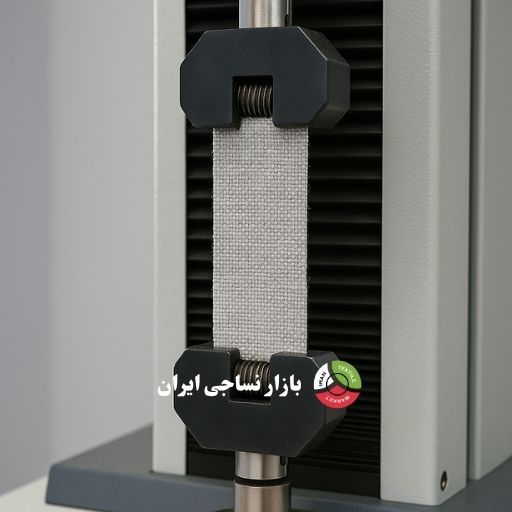 نمای نزدیک از آزمایش کشش روی پارچه تاری‌پودی در آزمایشگاه نساجی